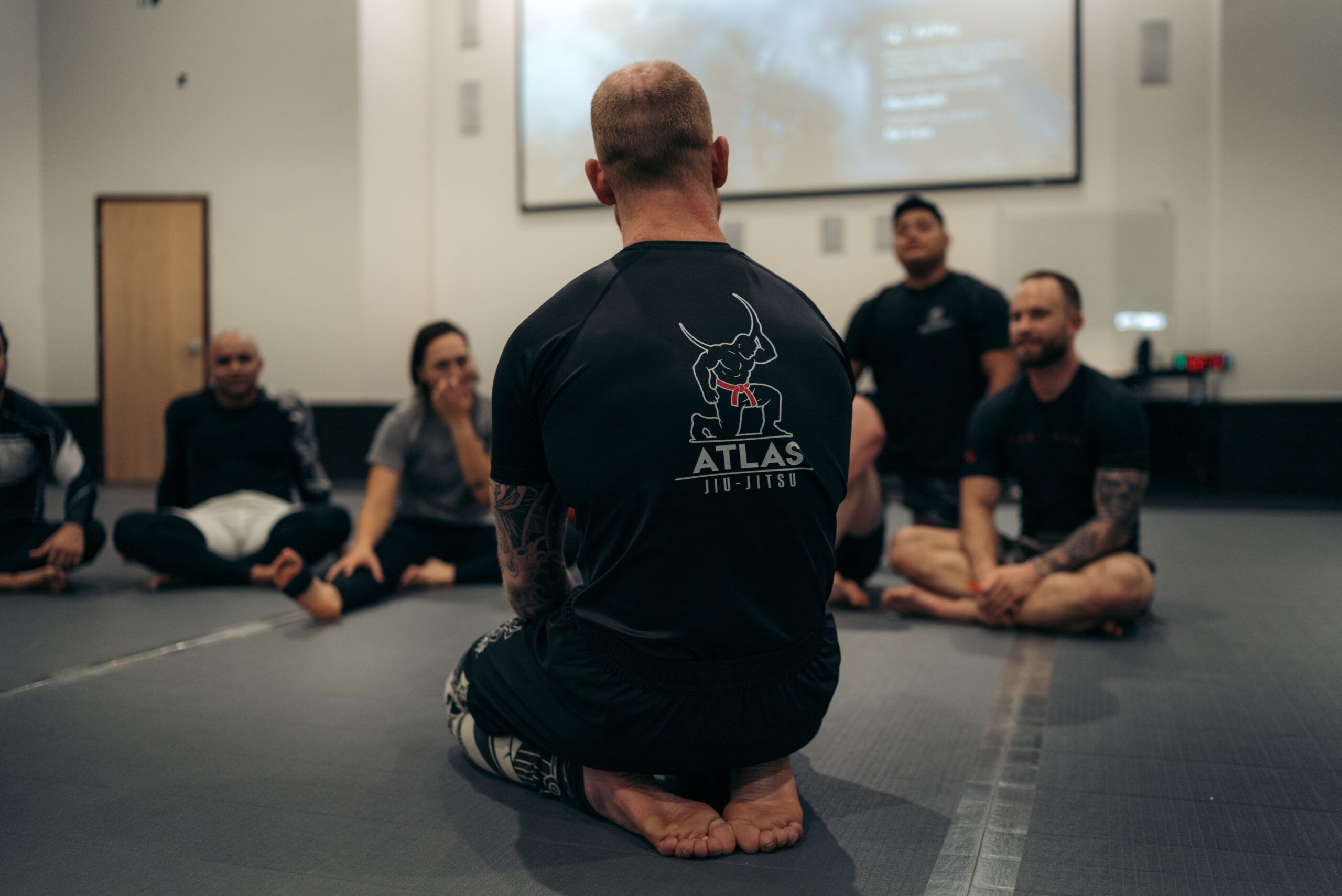Head instructor Chase Riddick teaching the class seated on the mat